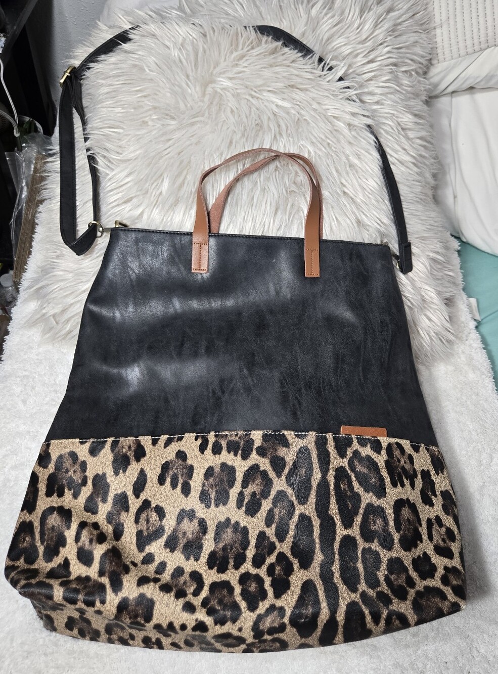 black faux-leather tote bag with a leopard-print base and brown carrying handles